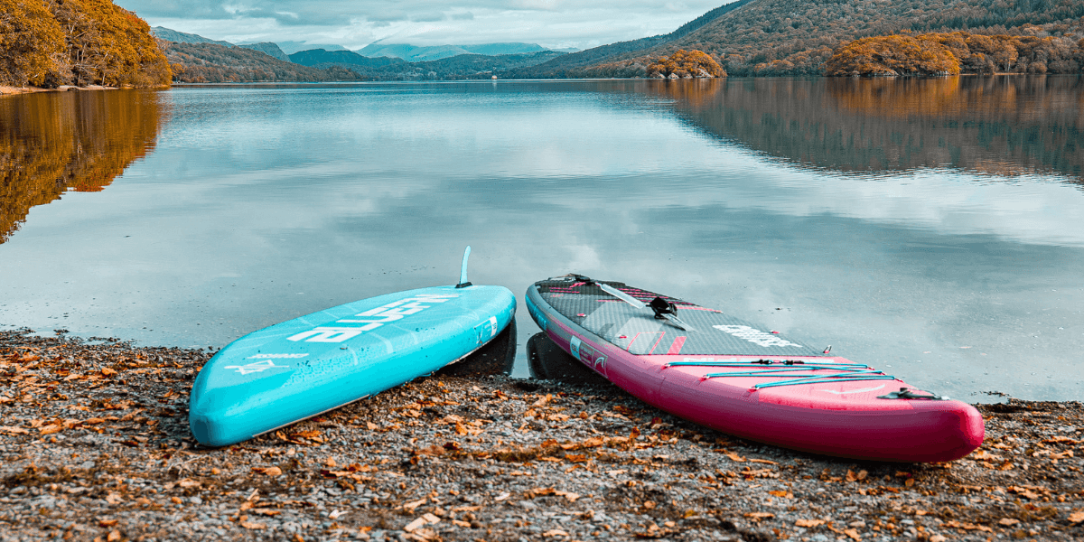 two paddleboards on a lake front with the backdrop of autumn leaves