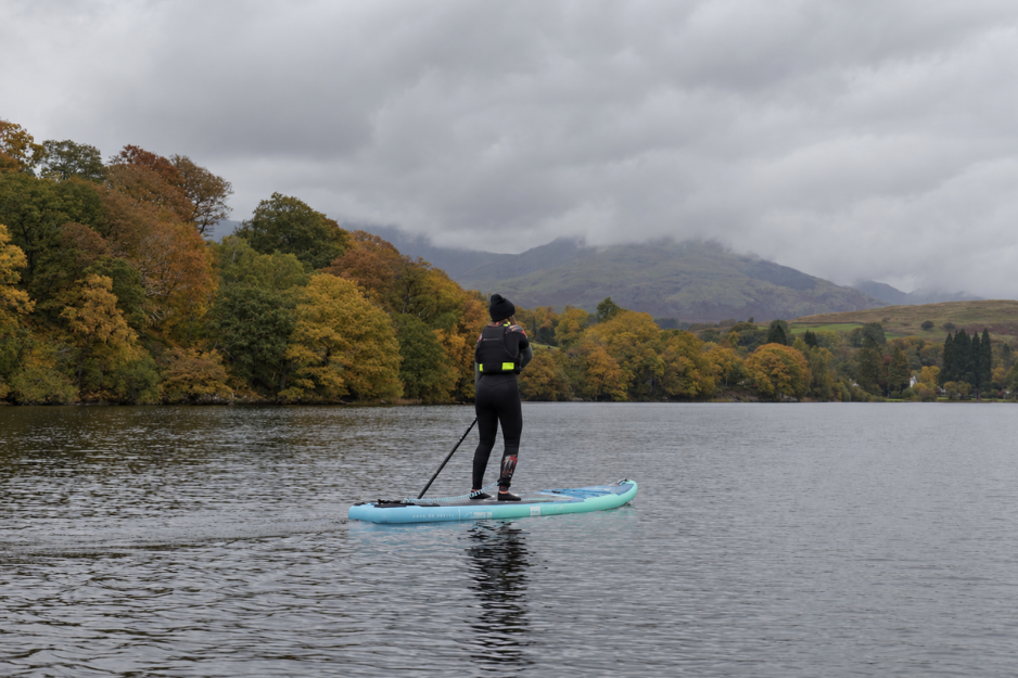 woman paddleboarding away from the camera on a lake