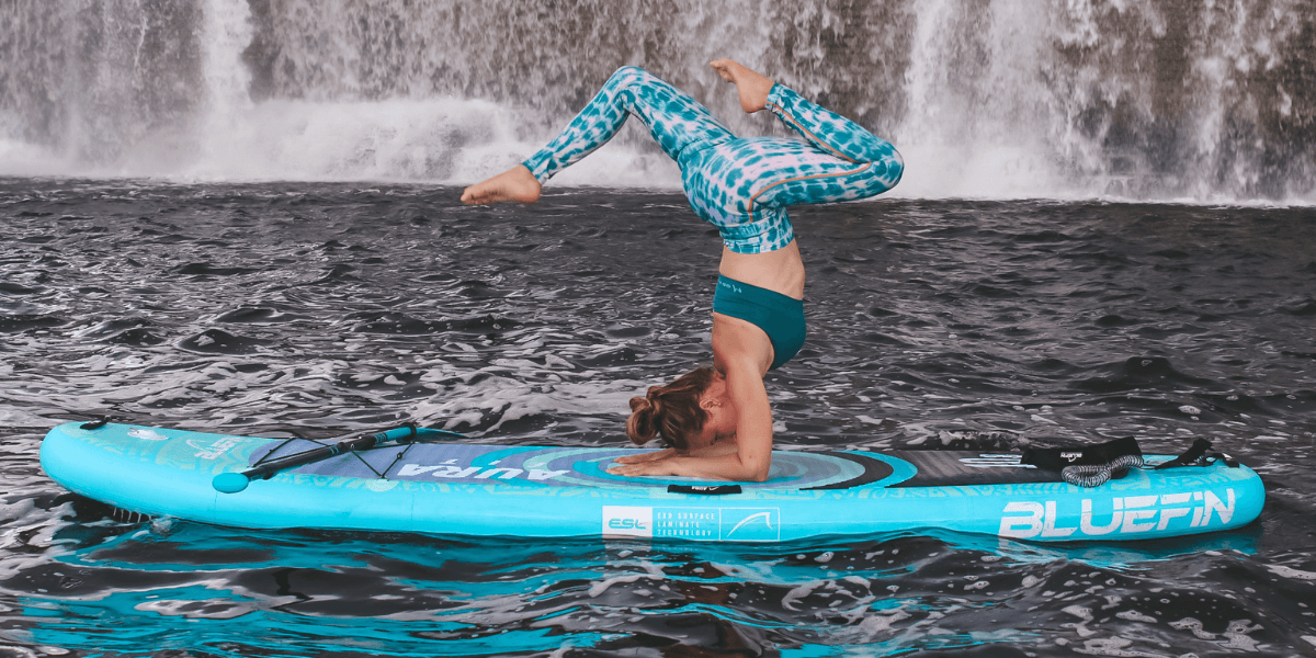 a lady on an aura fit paddleboard doing some sup yoga