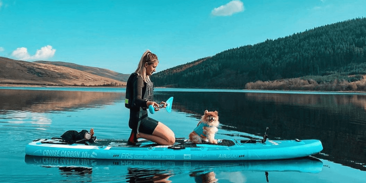 woman and dog on a paddleboard in a lake