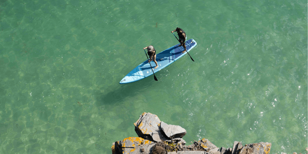 Two people on a tandem paddleboard in the ocean