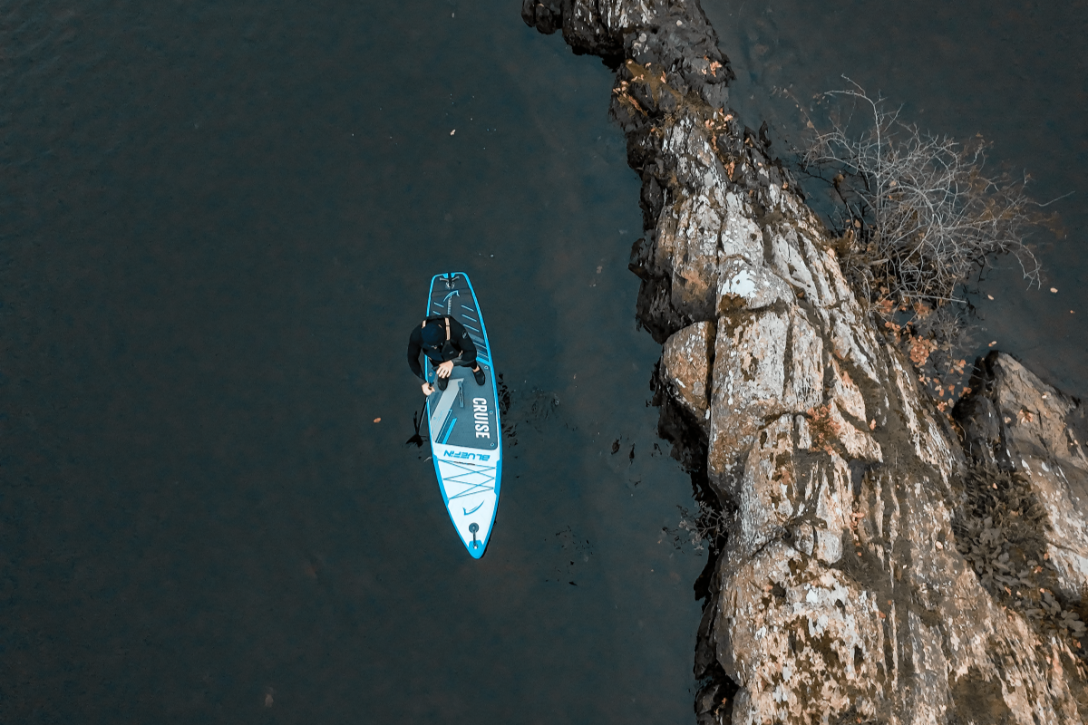 man paddleboarding on a lake on a Bluefin Cruise