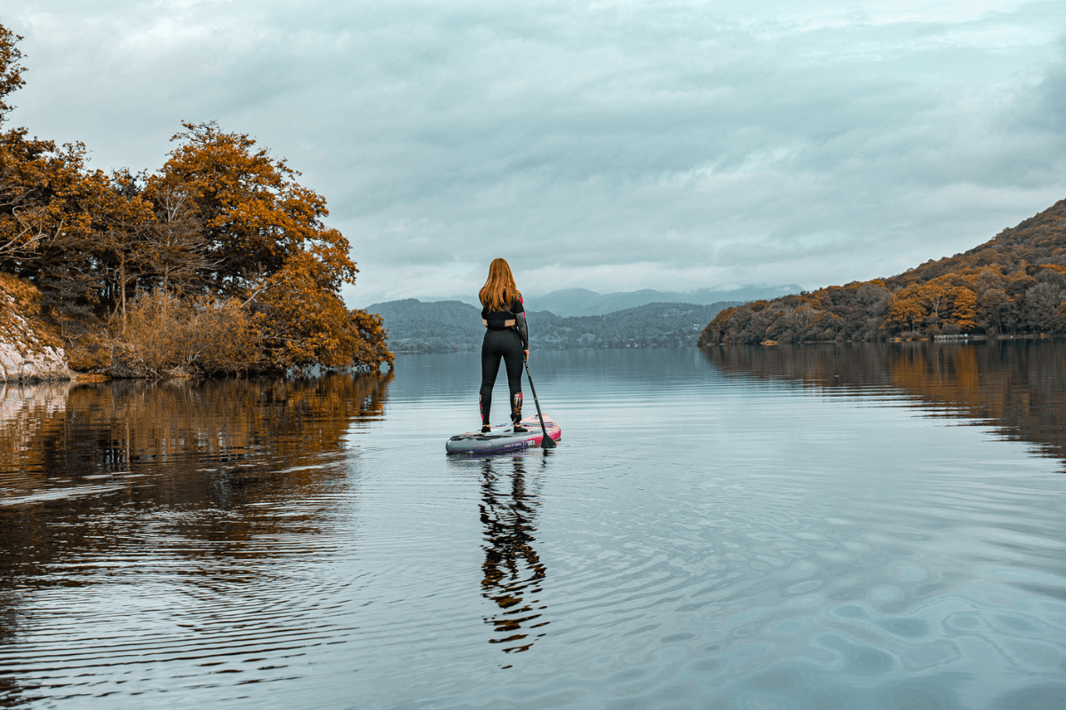 a woman paddleboarding in an autumnal lake