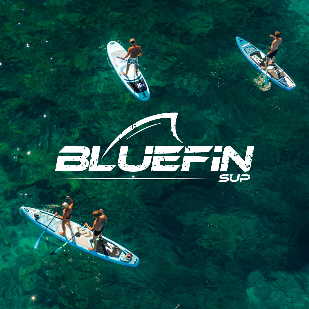 Four people paddle boarding on clear blue water with the Bluefin SUP logo prominently featured.