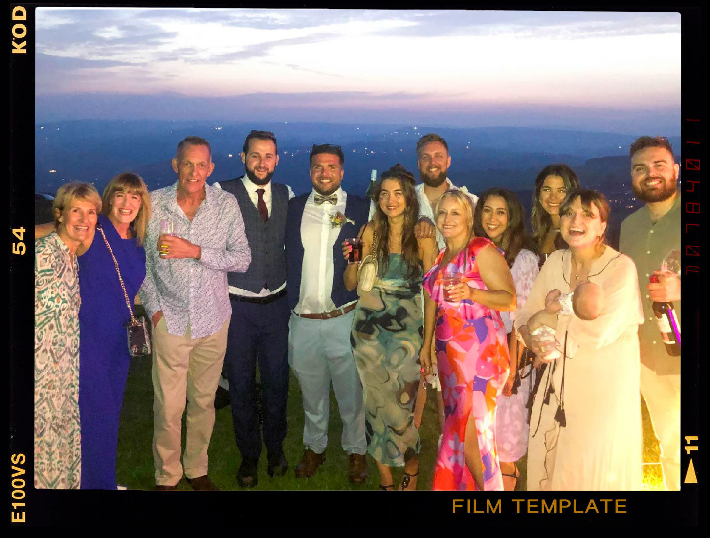 Group photo of 12 people celebrating at sunset, dressed in formal attire, with drinks in hand.