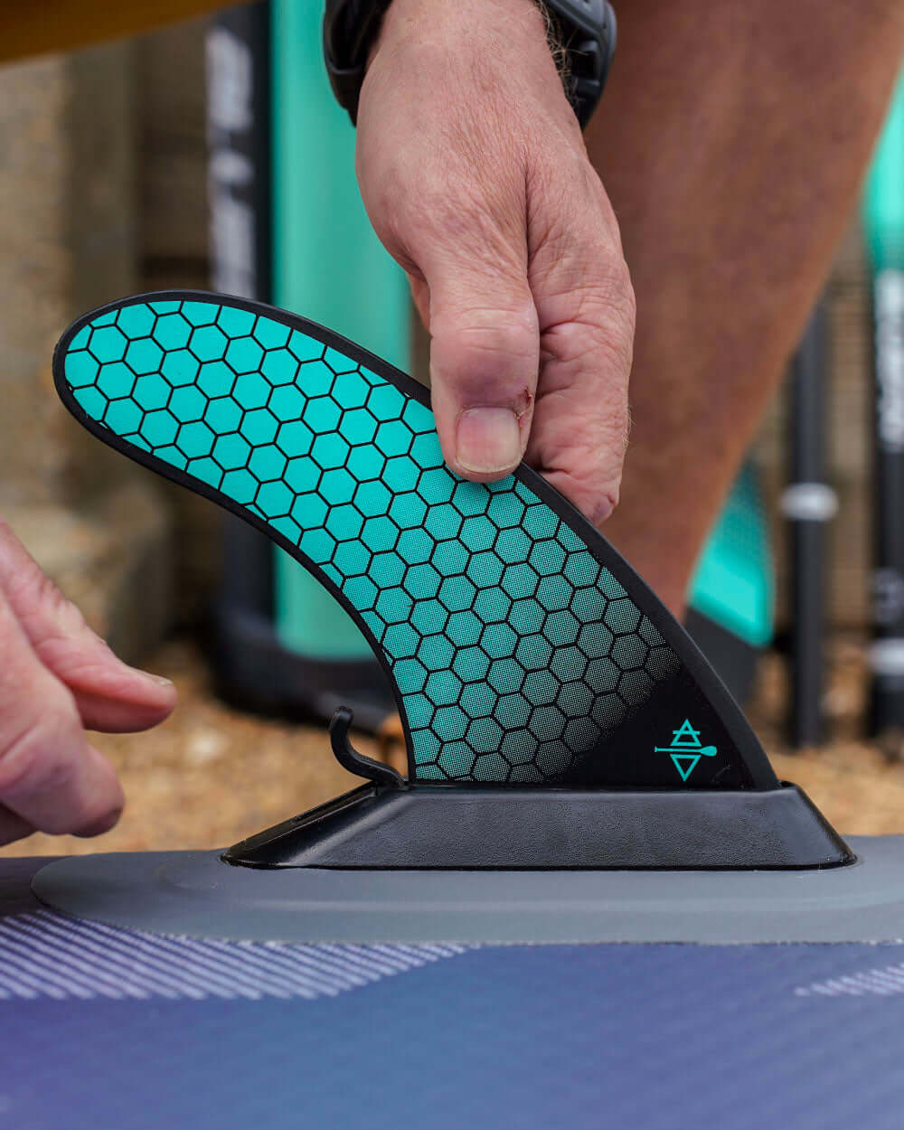 Person attaching a bluefin smartlock fin to a paddleboard