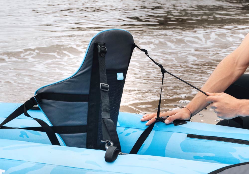 Adjusting the backrest on a Bluefin SUP near the water's edge.