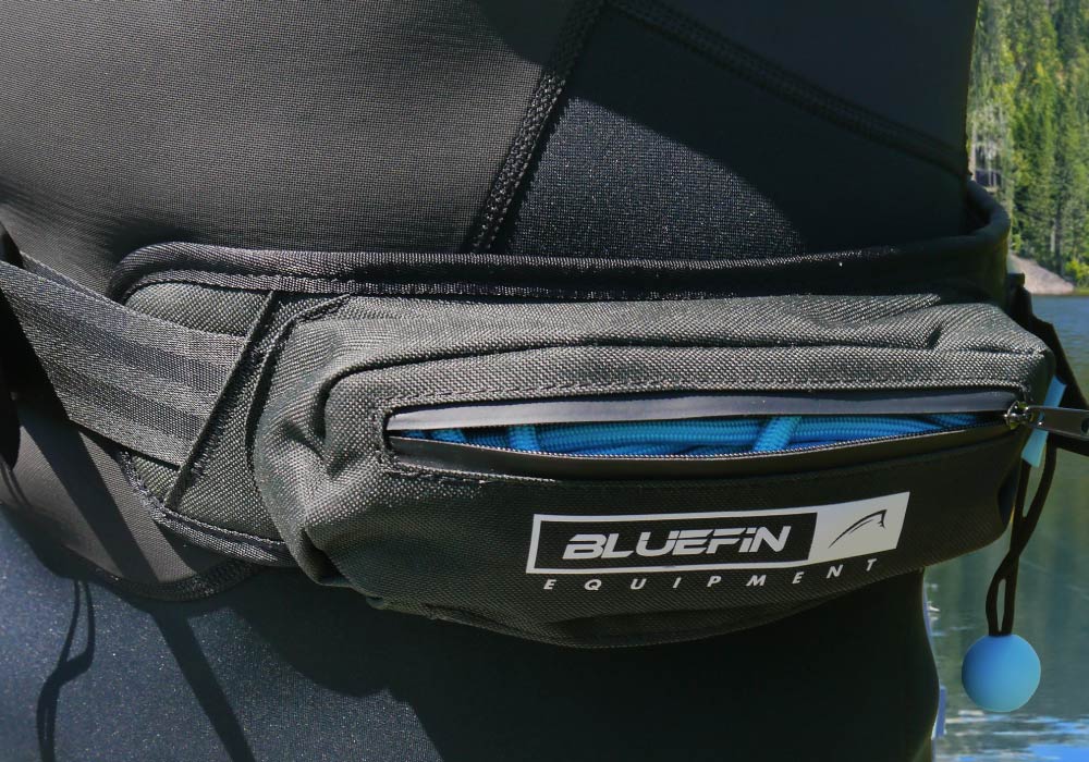 Black waist pack from Bluefin SUP featuring a zipper and adjustable straps, set against a natural backdrop.