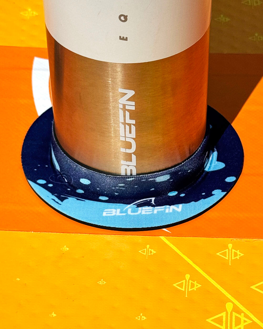 Hi-Drate water bottle with 'BLUEFIN' branding on a blue bottle dock on a Lite paddle board