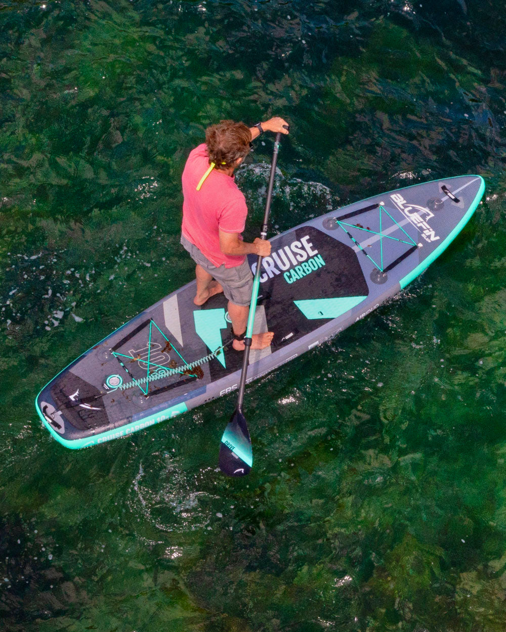 Person paddleboarding on a cruise stand-up paddleboard in clear water