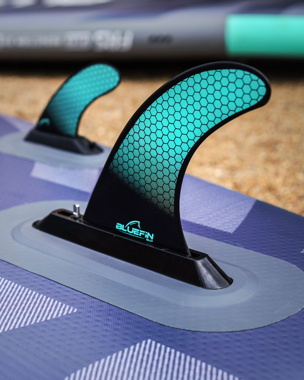 Close-up of the fins with 'Bluefin' logo attached on a stand up paddle board.