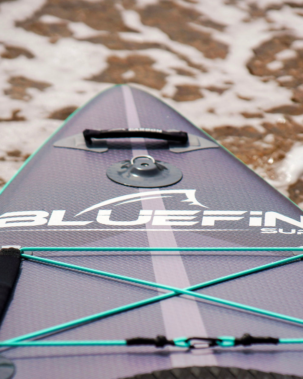 Close-up of the nose on a Bluefin SUP board with branding on a textured surface