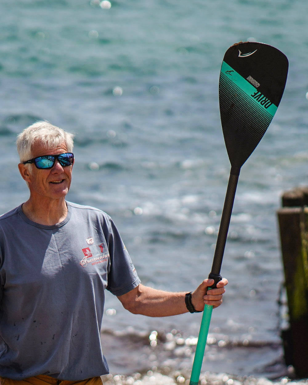 Man holding a paddle with water in the background