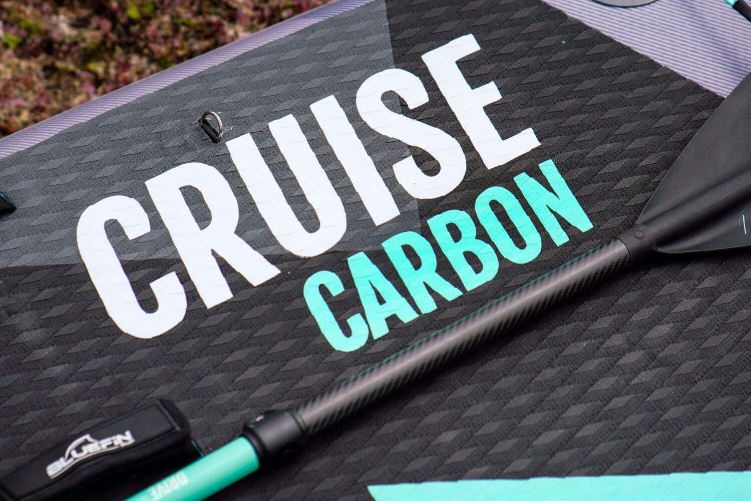 Close-up of a paddle board featuring the words "Cruise Carbon" and a carbon paddle.