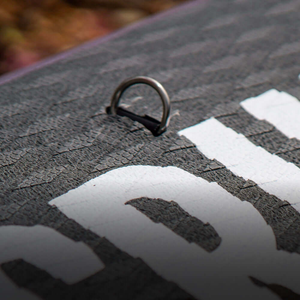 Close-up of a textured surface with a metal D-ring and a white printed logo.