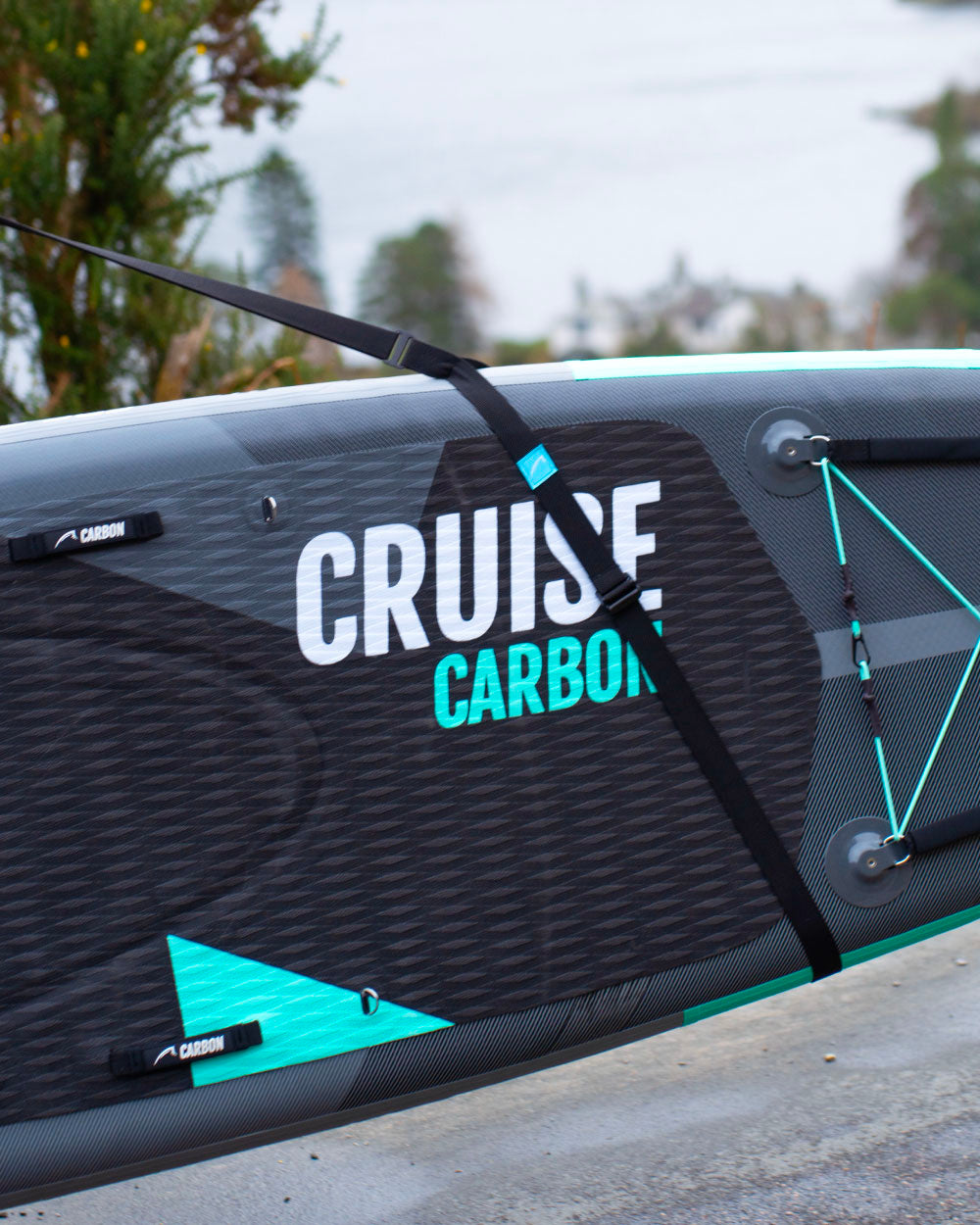 Close-up of a cruise carbon paddle board being held by the bluefin sup carry strap on a cloudy day.