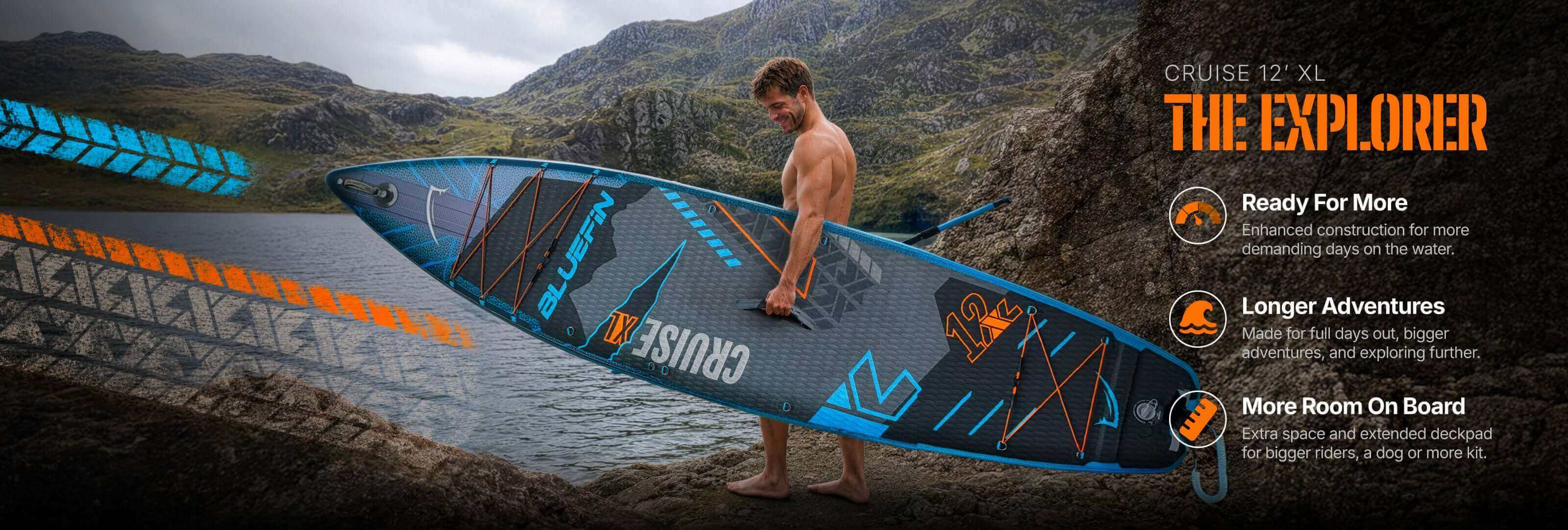 Inflatable paddleboard with textured deck, center fin, and orange and blue accents in a scenic outdoor setting