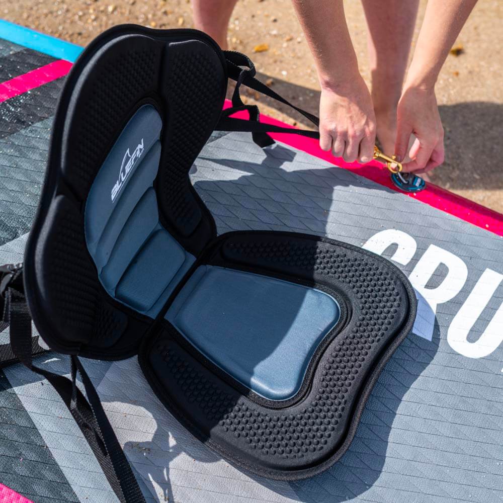 Comfortable Bluefin SUP seat cushion on a paddleboard with a person securing the strap.