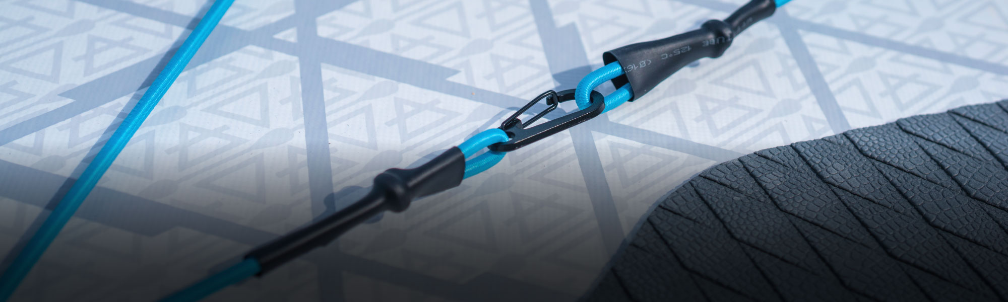 Close-up of a blue leash connection on a paddleboard surface with patterned texture.