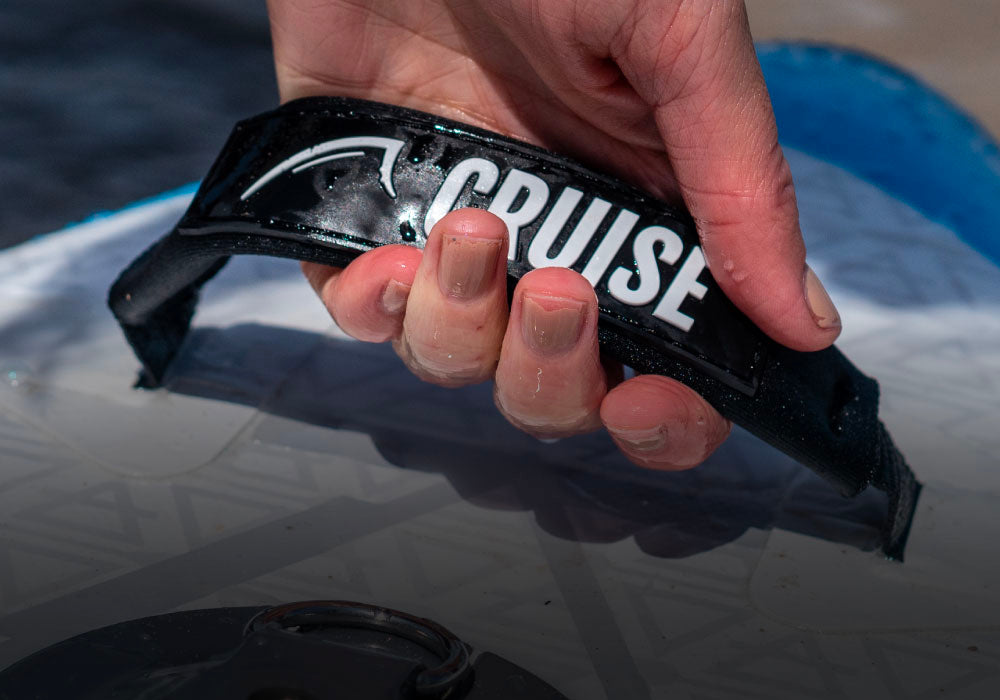 Hand holding a water-resistant handle labeled "CRUISE" on a paddleboard.