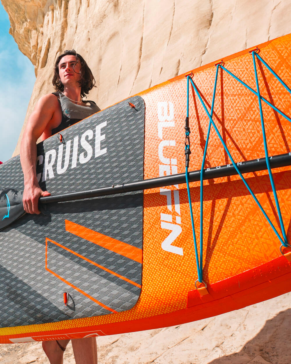 Man carrying an Orange Sunset Bluefin cruise 10'8 sup paddle board
