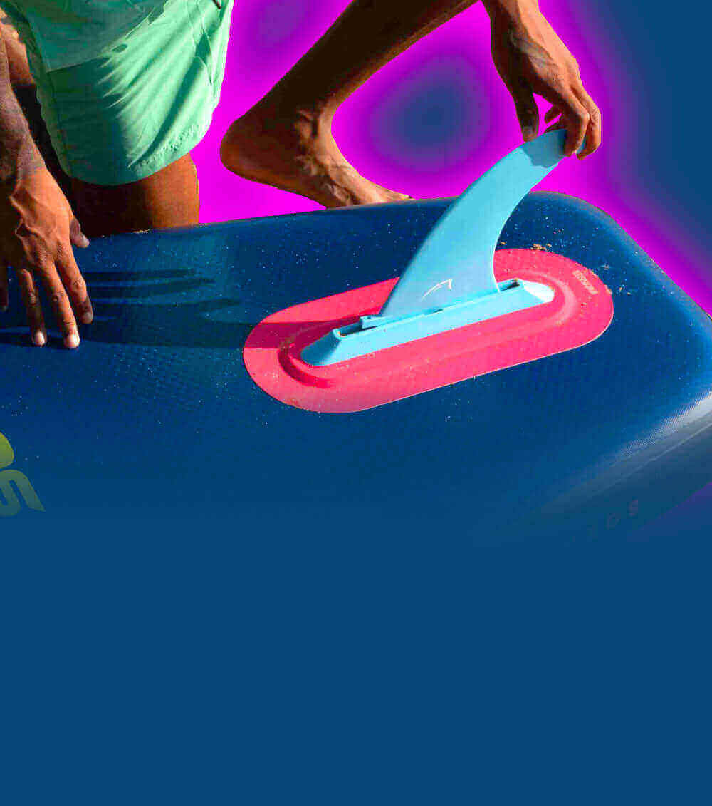 Person attaching a blue fin to a paddleboard, showcasing vibrant colors and outdoor activity.