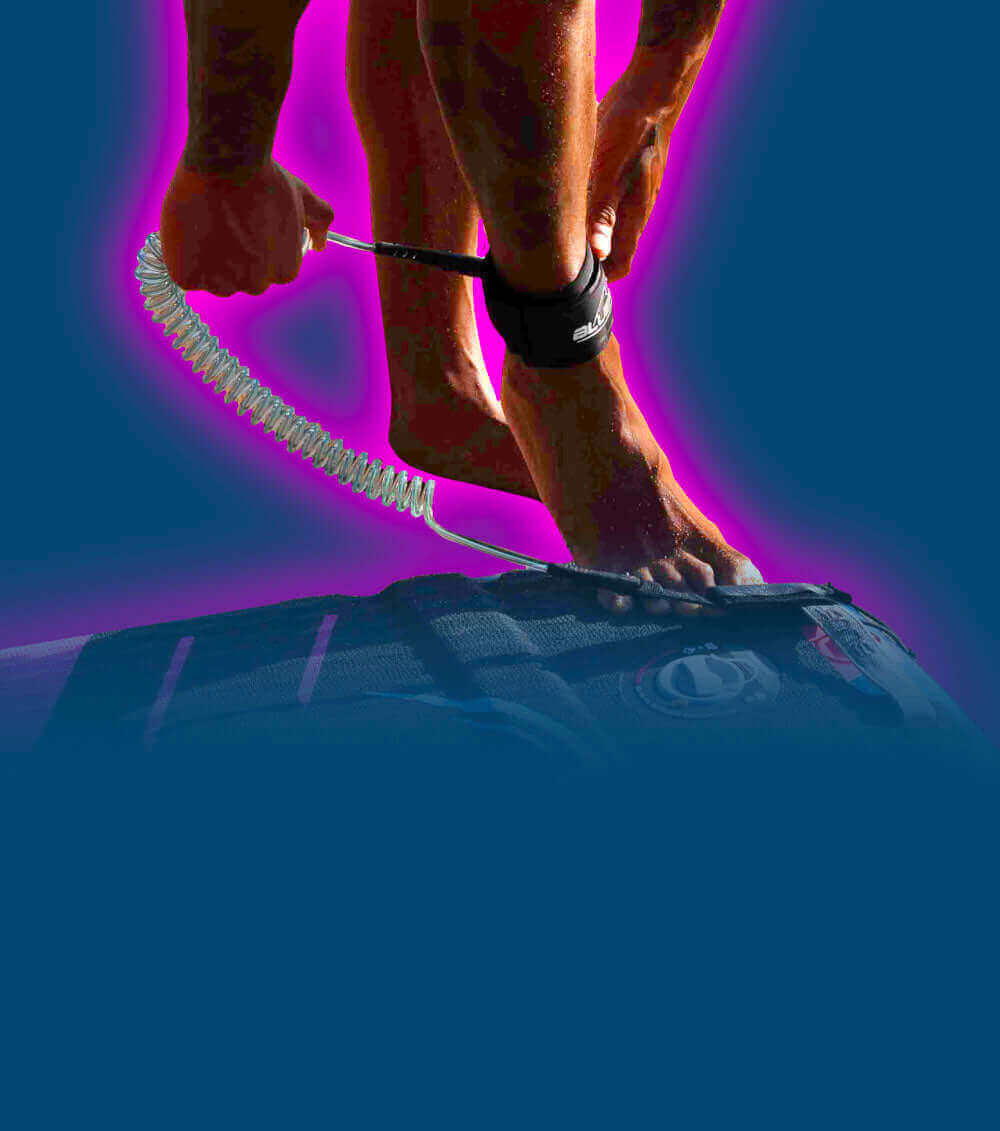 Person attaching a coil leash to their ankle while standing on a paddleboard.