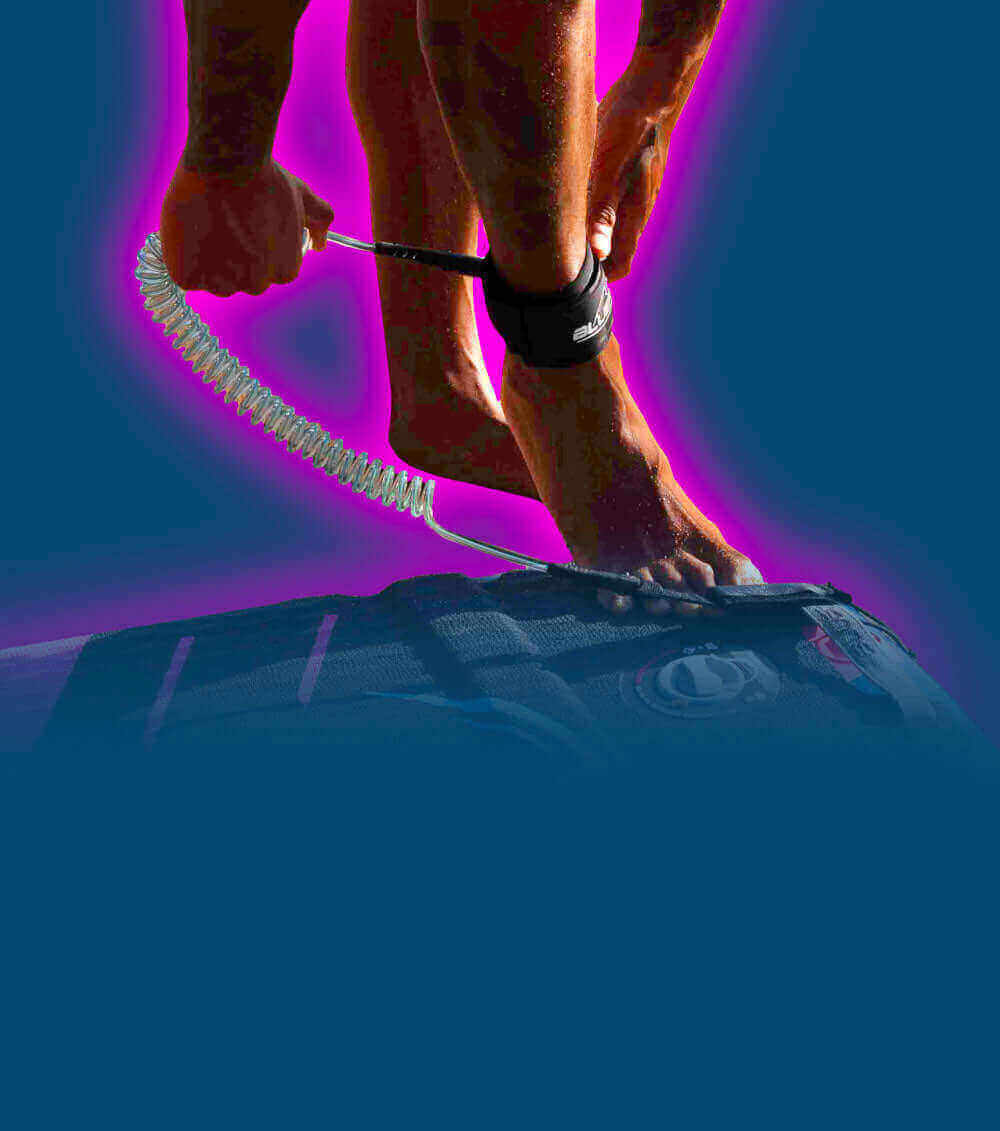 Person attaching a coil leash to their ankle while standing on a paddleboard.