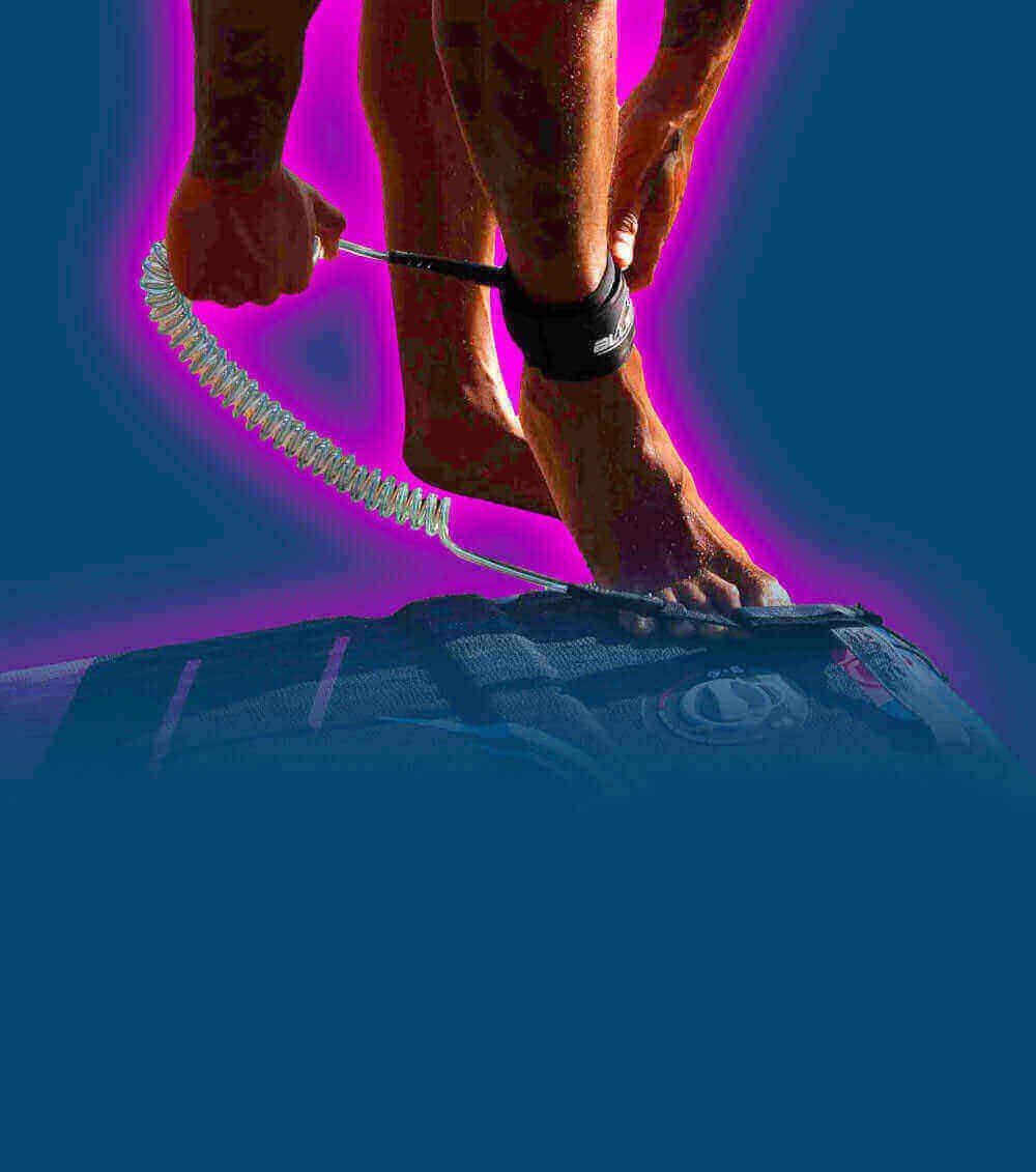Person attaching a coil leash to their ankle while standing on a paddleboard.