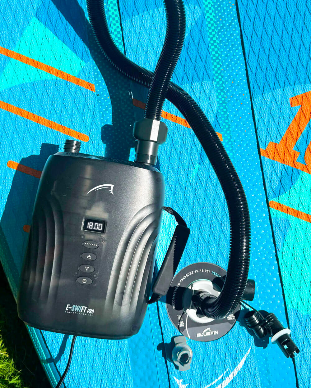 A portable electric pump with a digital display photographed on a Lite paddle board. For inflating a stand up paddle board