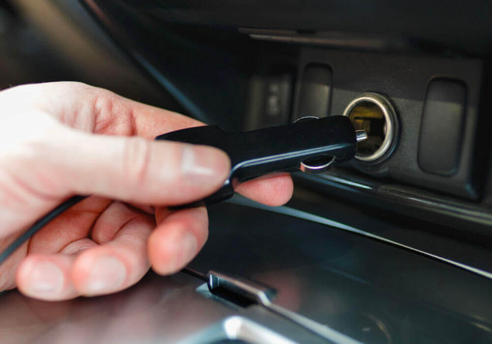 Hand inserting a car key into the ignition slot in a vehicle's interior.
