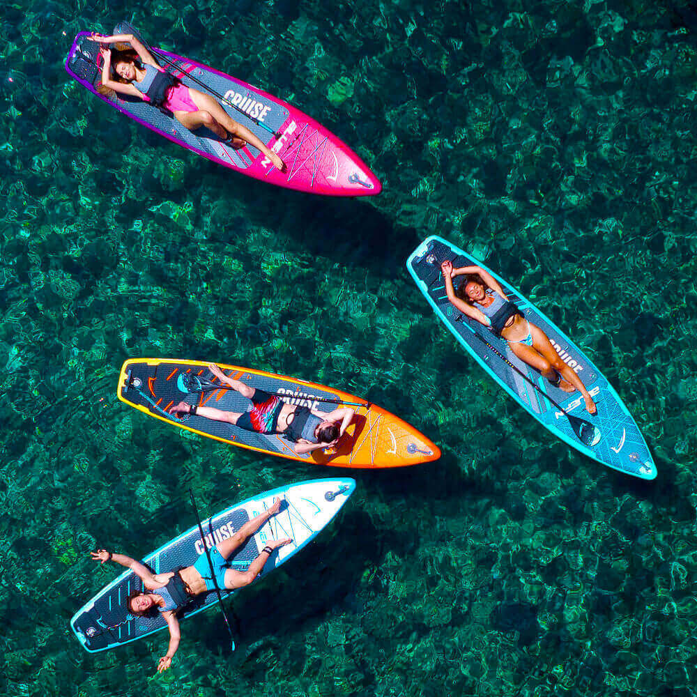 Four friends relaxing on colorful paddle boards in clear blue water. Perfect for summer fun!