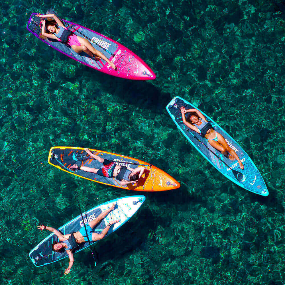 Four friends relaxing on colorful paddle boards in clear blue water. Perfect for summer fun!