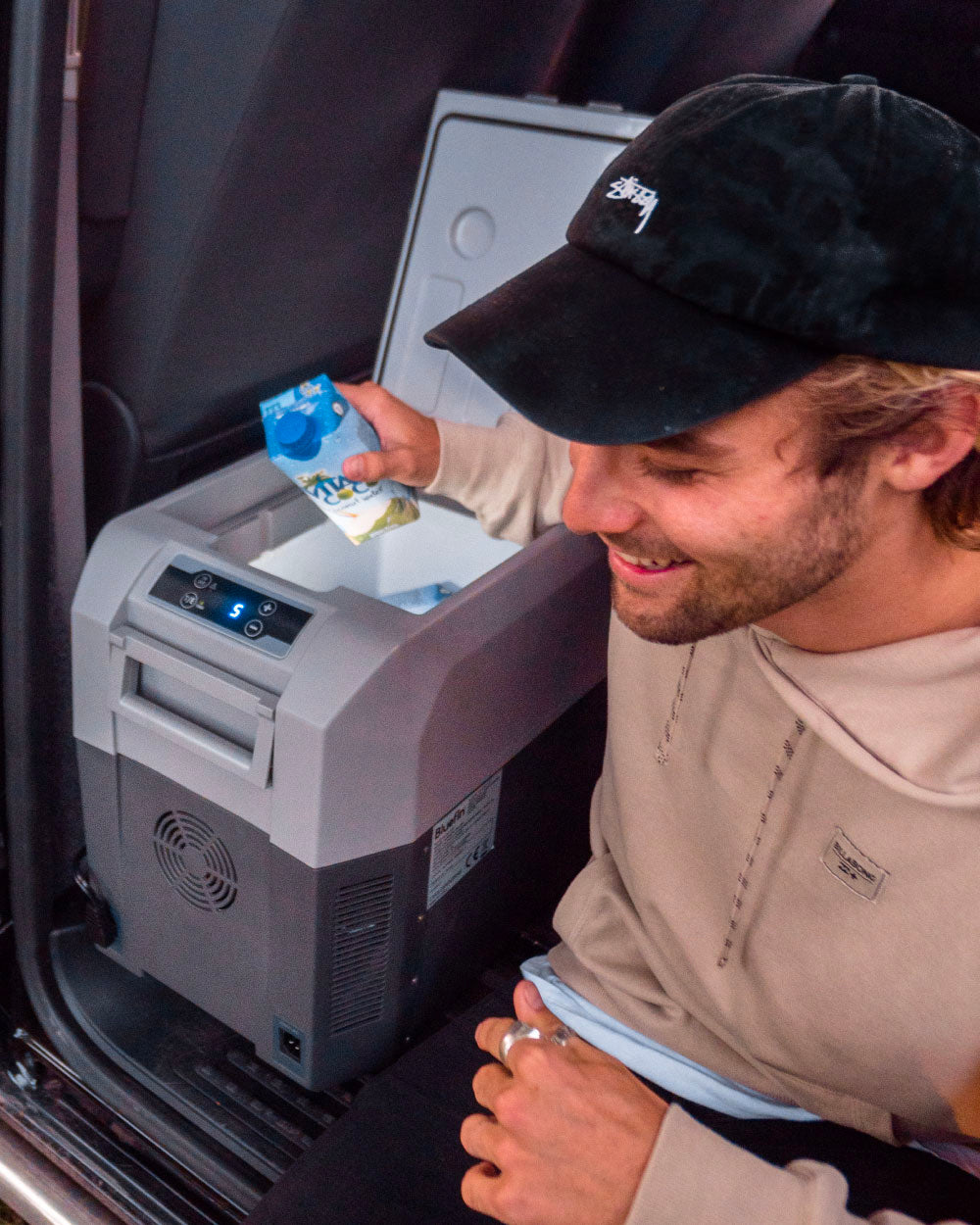 Person using a portable refrigerator in a vehicle