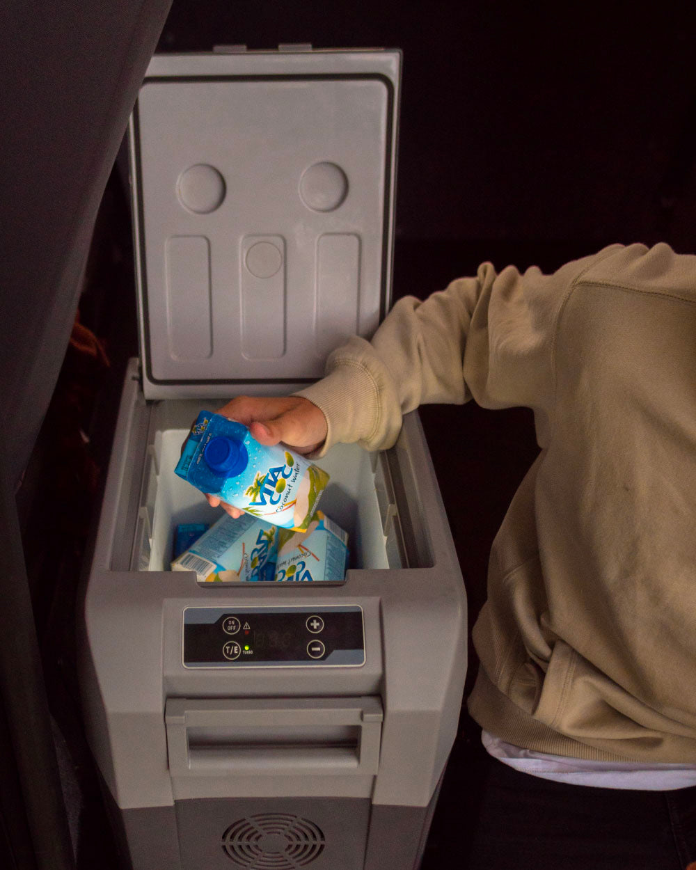 Person placing a drink into a small portable refrigerator.