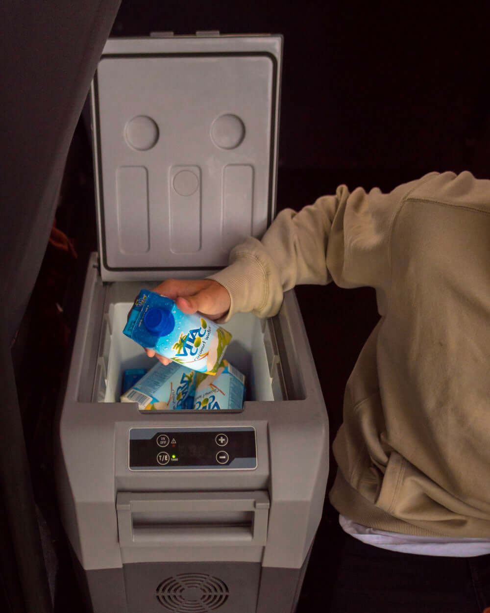Person placing a drink into a small portable refrigerator.