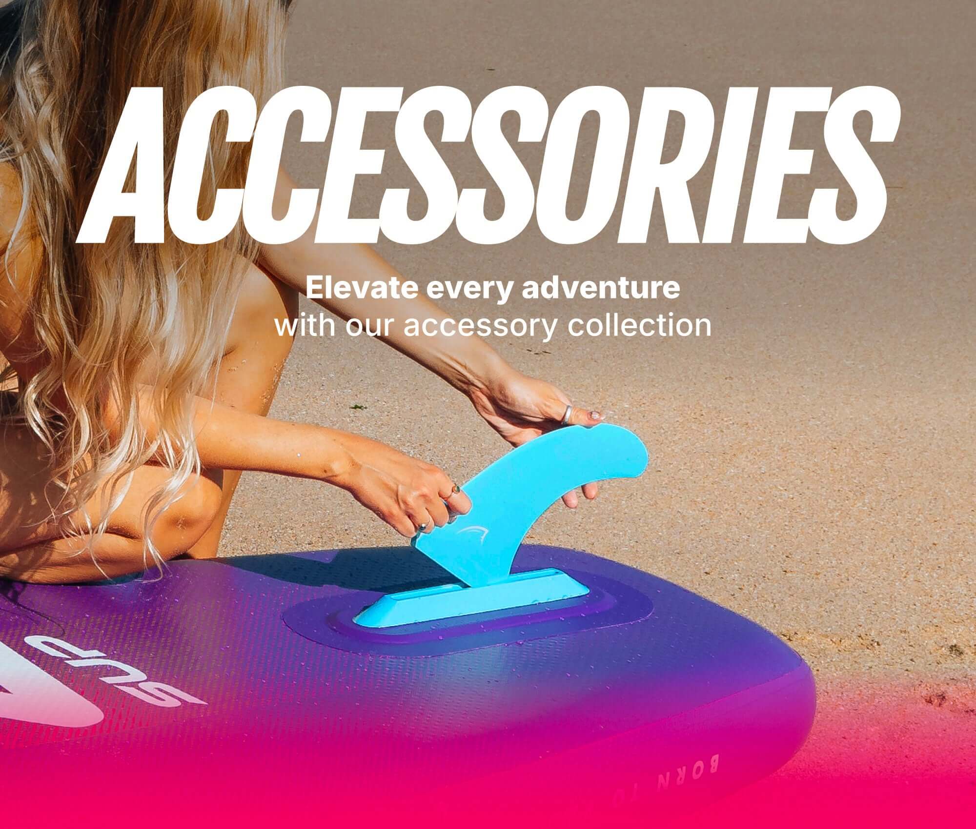 Person attaching a blue fin to a purple inflatable paddleboard on a sandy beach