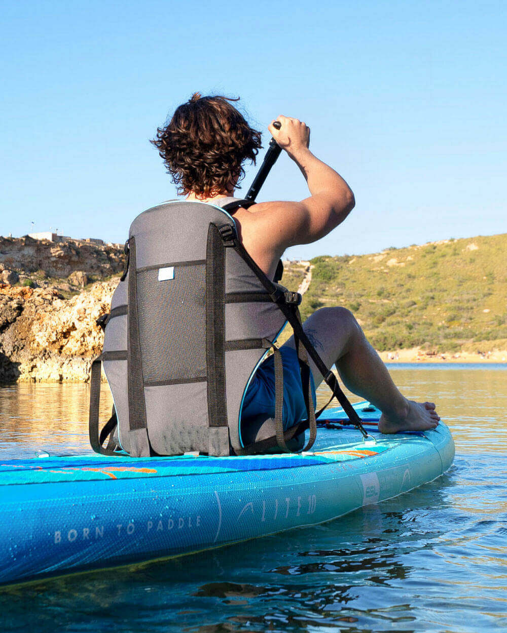 Person paddleboarding with the Bluefin kayak seat attachment on a clear day.