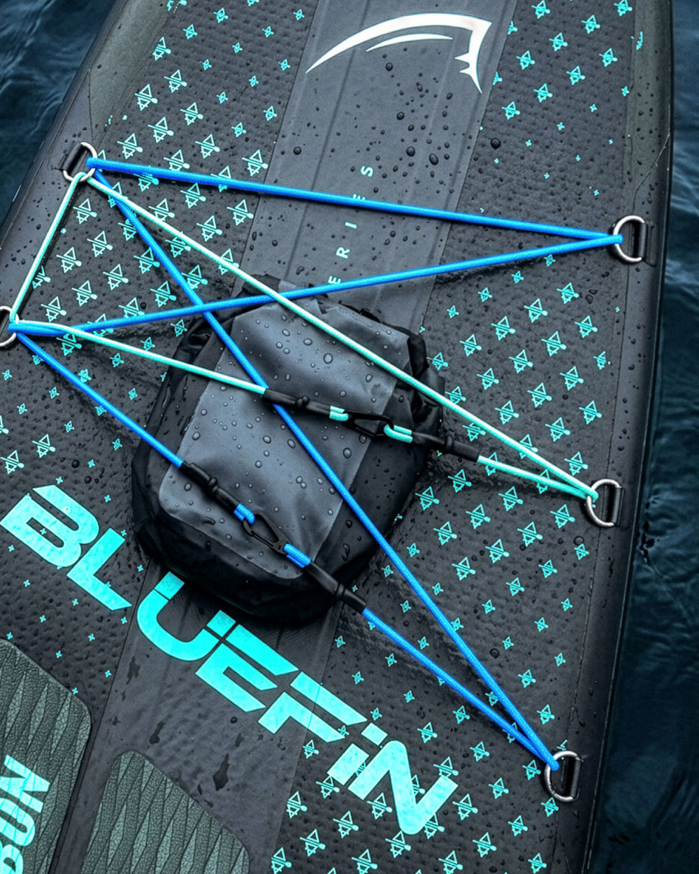 Inflatable paddleboard with blue bungee cords, textured surface, and a black storage bag on top