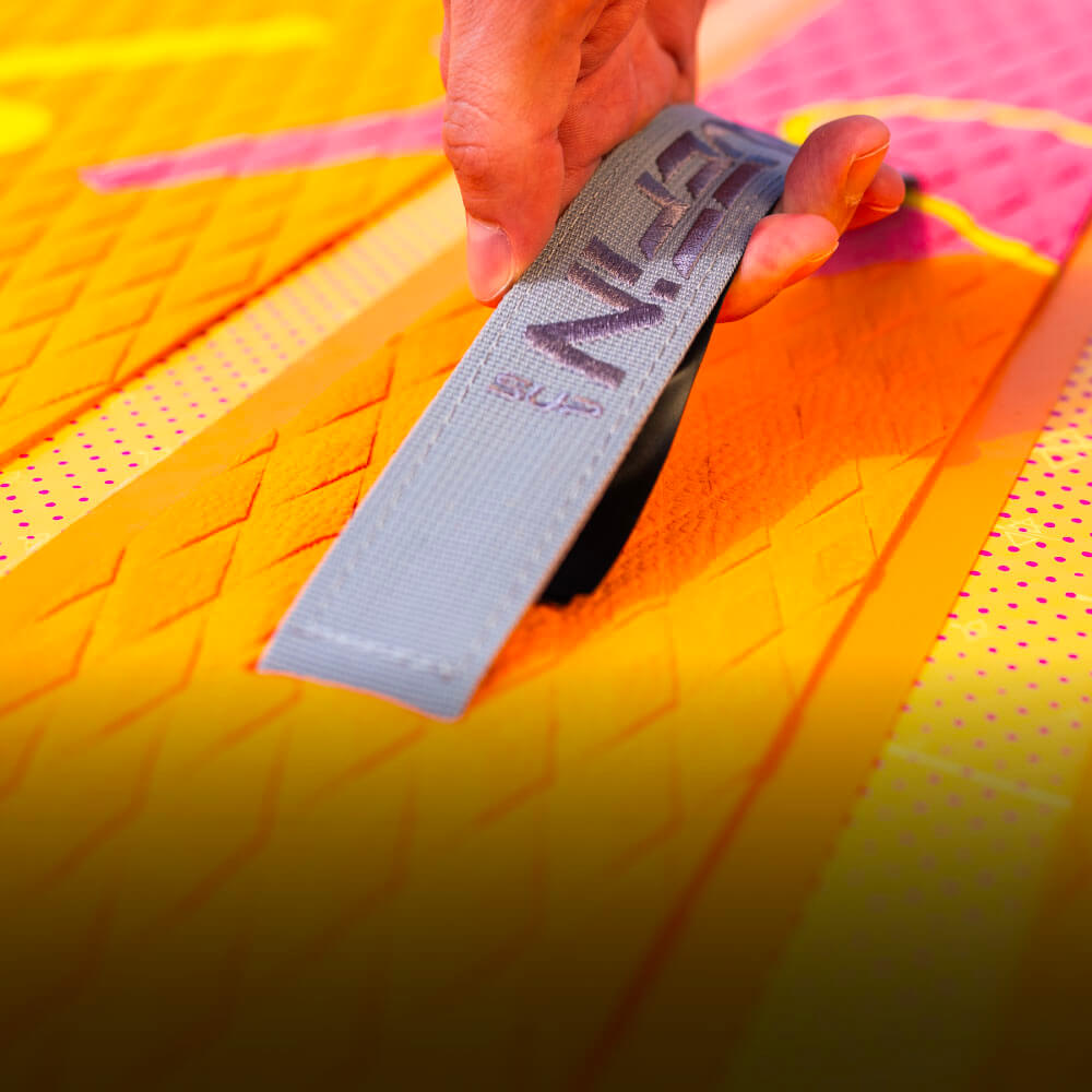 Hand adjusting a strap on a vibrant Bluefin SUP paddleboard with textured surface.