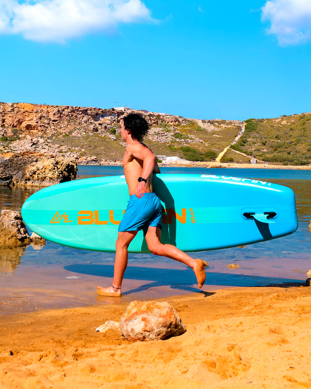 Man running on the beach with a Blue Lagoon 10' Lite Bluefin sup paddle board