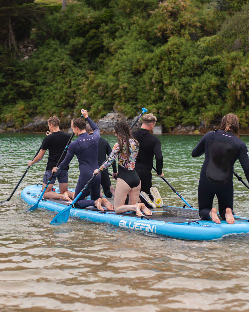 Group of people paddleboarding on a mammoth sup in lake with trees in the background