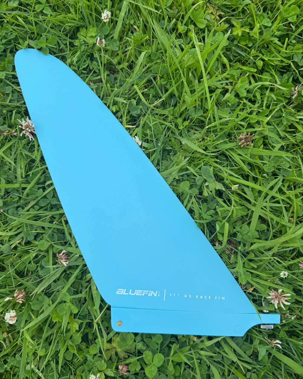 Bluefin 11" US race fin on grass, showcasing a bright blue color and smooth design.