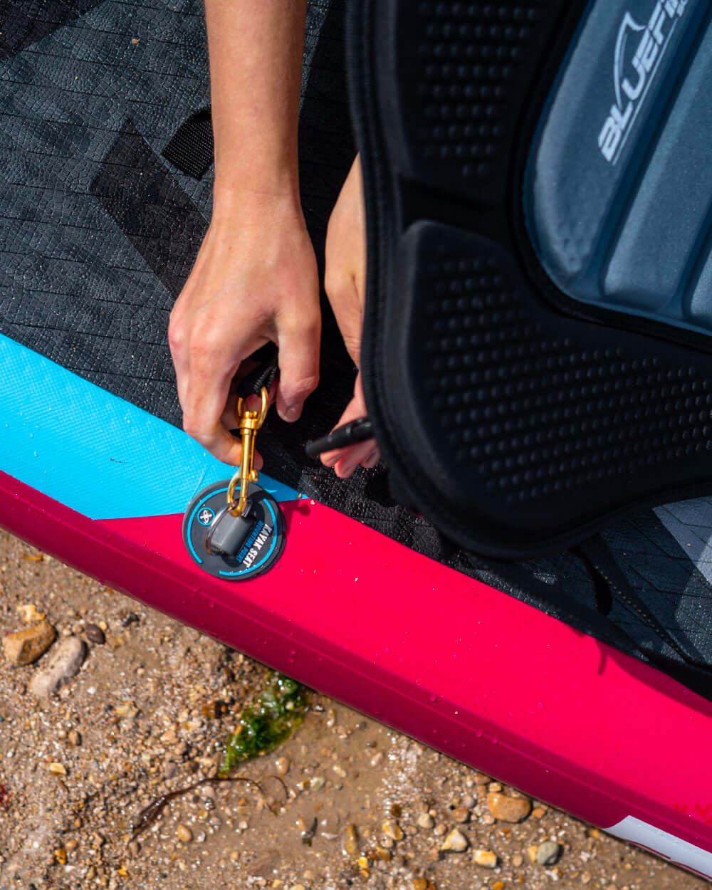 person using the d-ring attachments to secure the kayak seat to the paddle board