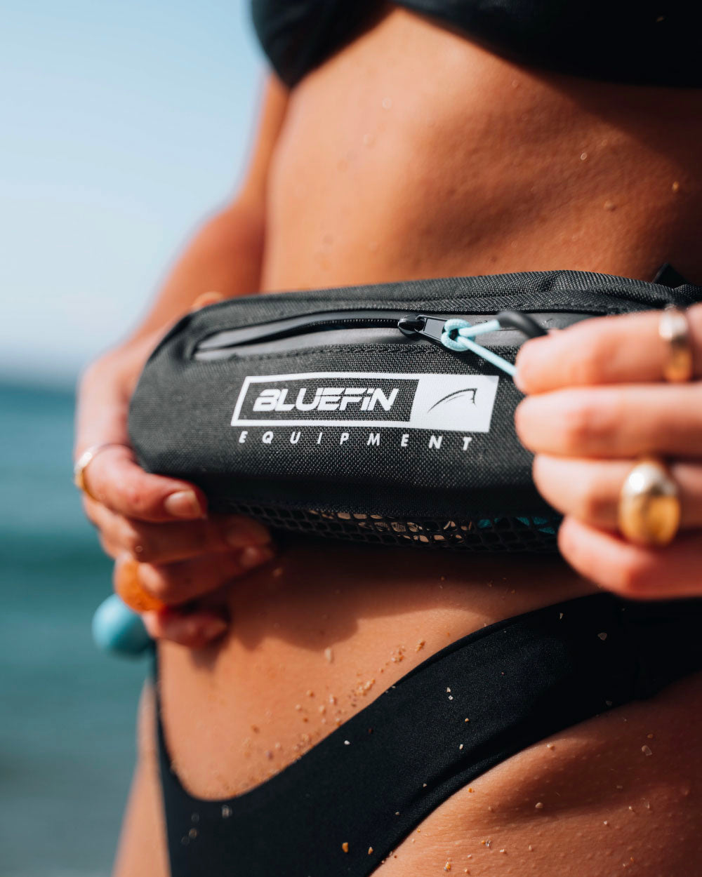 Person using the zip on the pocket of a bluefin quick re-leash belt for an paddle board