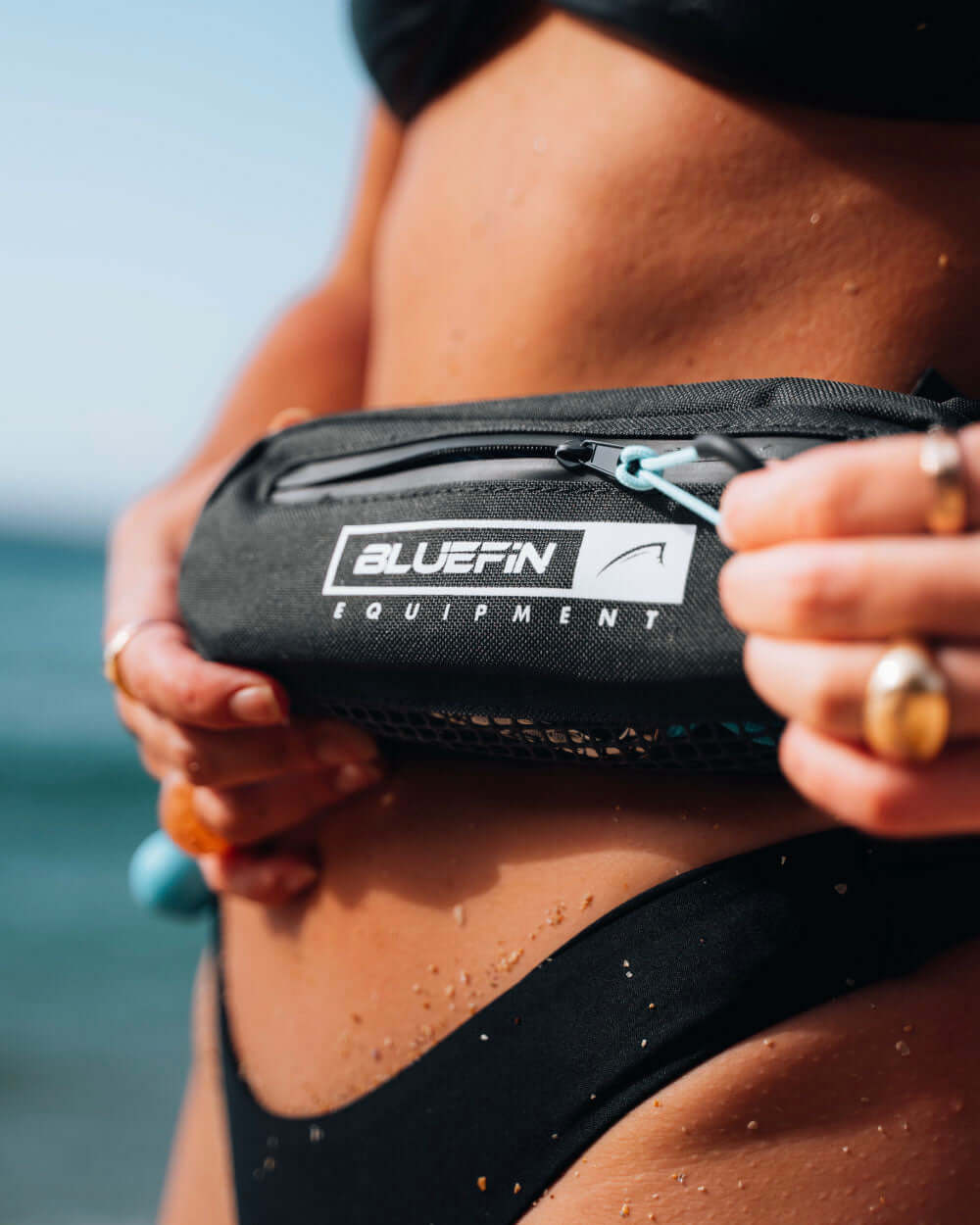 Person using the zip on the pocket of a bluefin quick re-leash belt for an paddle board