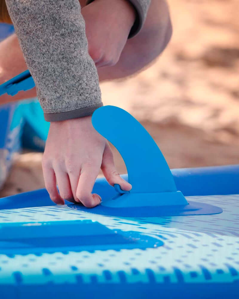someone attaching a bluefin smartlock fin to an inflatable sup