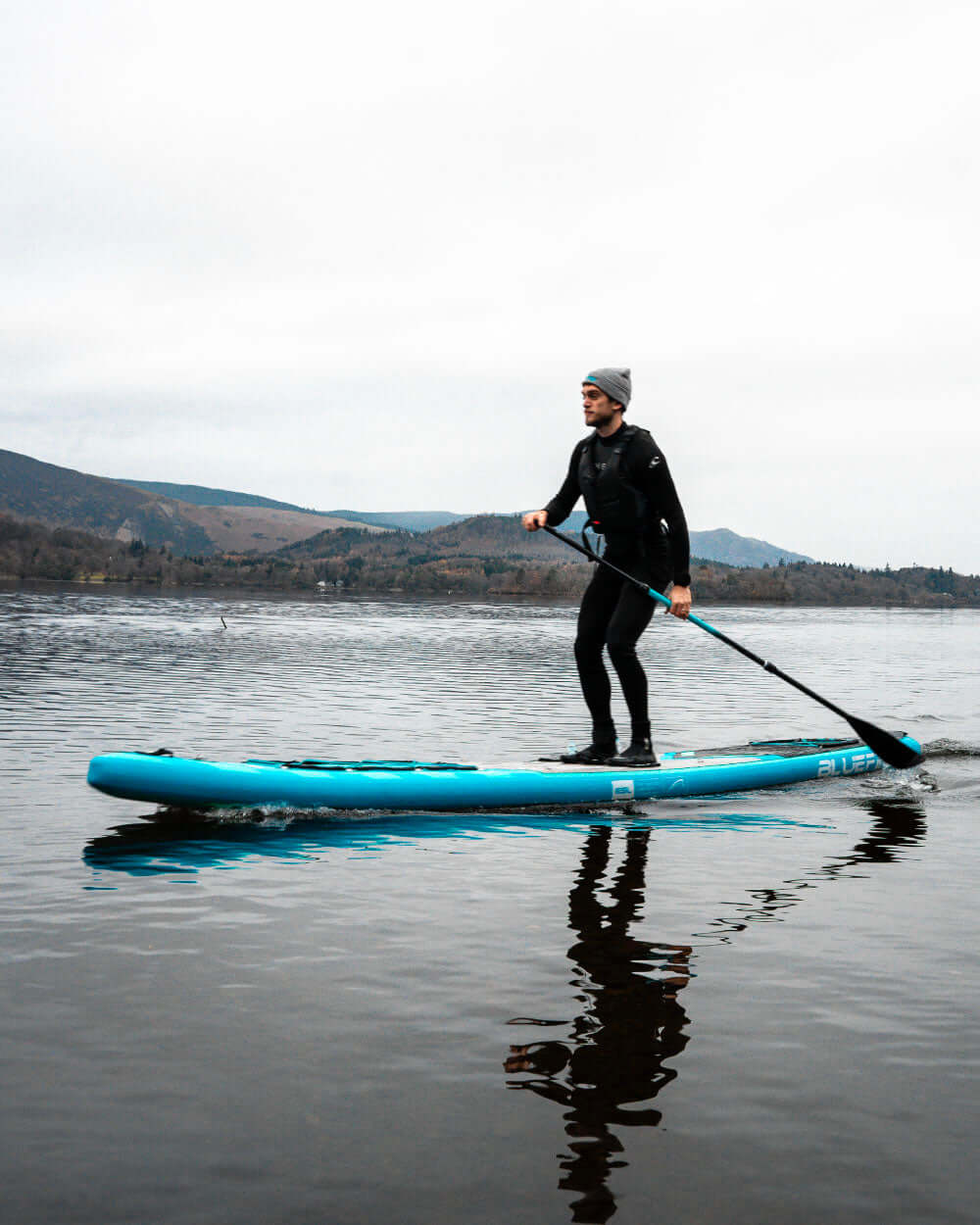Person paddleboarding on a lake with mountains in the background