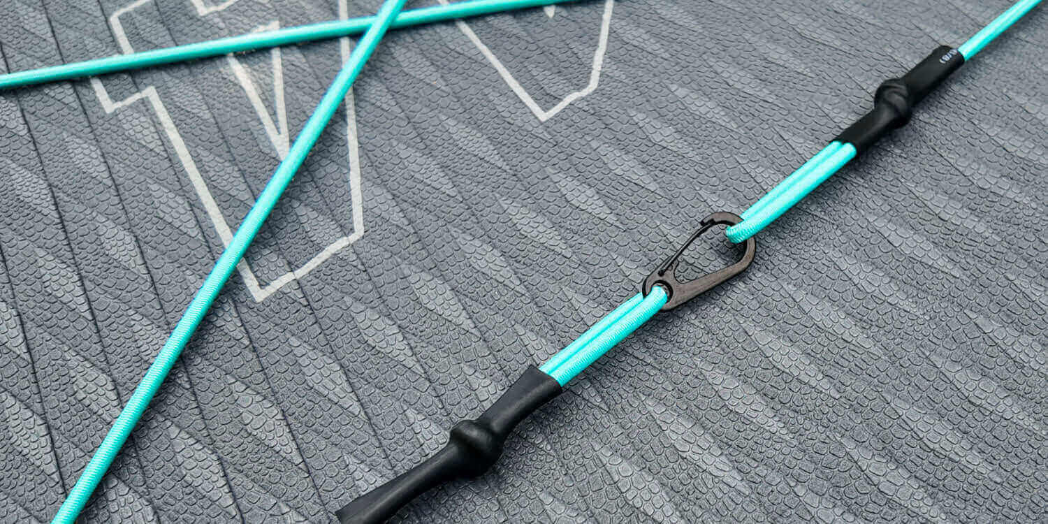 Close-up of a turquoise paddleboard accessory on a textured gray surface.