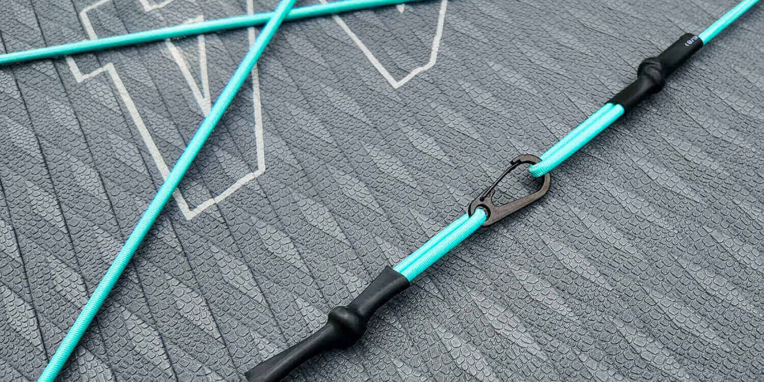 Close-up of a turquoise paddleboard accessory on a textured gray surface.